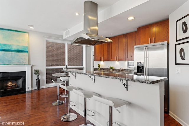 2315 W Wabansia Ave Unit 3Ne, Chicago, IL 60647 - kitchen with island range hood, brown cabinetry, dark wood finished floors, stainless steel fridge with ice dispenser, and a kitchen bar