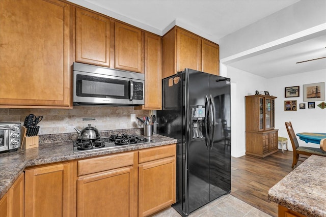 1905 Easy St, Urbana, IL 61802 - kitchen with stainless steel microwave, black fridge with ice dispenser, gas cooktop, tasteful backsplash, and brown cabinetry