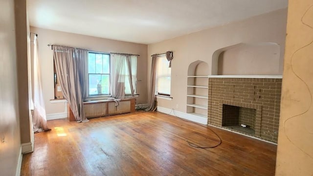 5330 W Foster Ave, Chicago, IL 60630 - unfurnished living room with built in shelves, wood finished floors, and a brick fireplace