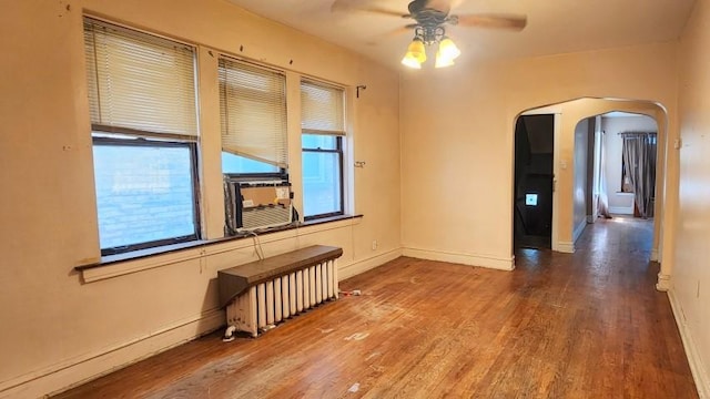 5330 W Foster Ave, Chicago, IL 60630 - unfurnished room with radiator heating unit, arched walkways, a ceiling fan, and wood finished floors