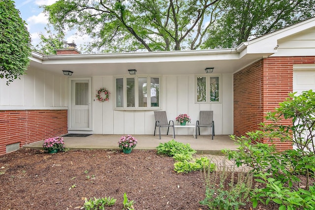 6231 W 127th Pl, Palos Heights, IL 60463 - view of exterior entry with board and batten siding, a chimney, brick siding, and covered porch
