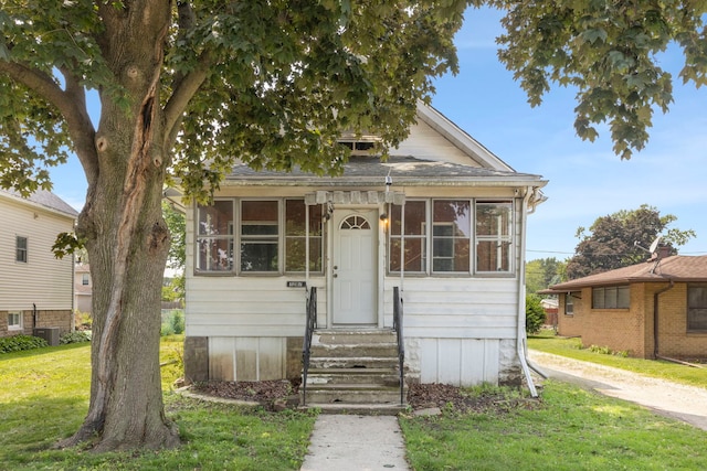 1207 Oakland Ave, Joliet, IL 60435 - view of front of house with entry steps, a front yard, and a sunroom