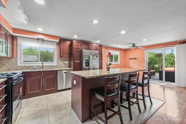 611 Brewster Ln, Schaumburg, IL 60193 - kitchen with appliances with stainless steel finishes, a sink, a kitchen breakfast bar, decorative backsplash, and a center island