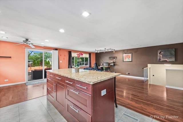 611 Brewster Ln, Schaumburg, IL 60193 - kitchen with a center island, light tile patterned floors, a kitchen breakfast bar, ceiling fan, and baseboards