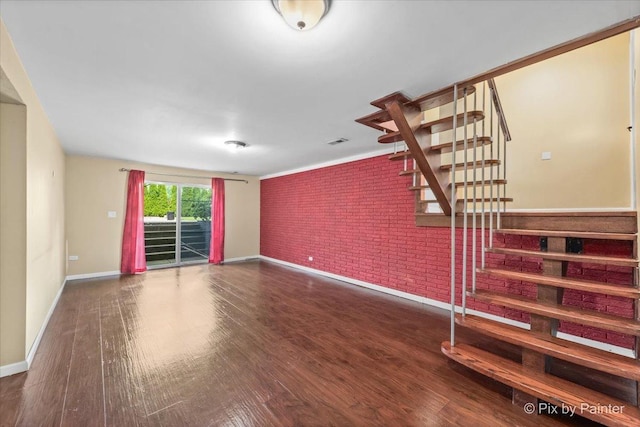 611 Brewster Ln, Schaumburg, IL 60193 - unfurnished living room featuring brick wall, stairway, baseboards, and wood finished floors