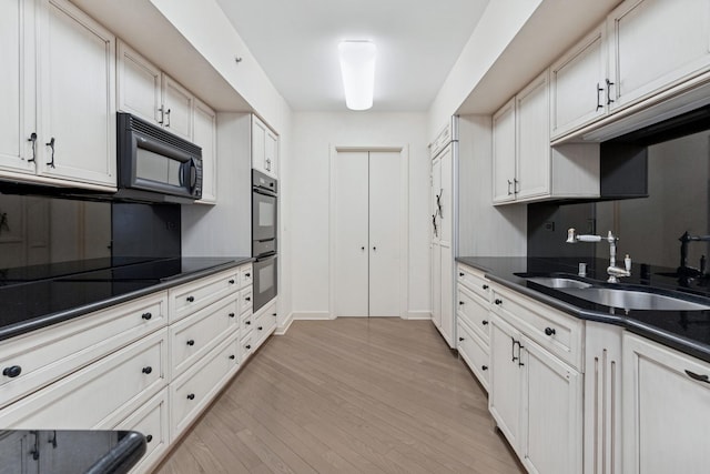 132 E Delaware Pl Unit 5504, Chicago, IL 60611 - kitchen with black appliances, a sink, dark countertops, light wood-type flooring, and white cabinetry