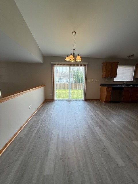 916 Bluegrass Ln, Plano, IL 60545 - unfurnished dining area with a chandelier, light wood-style floors, baseboards, vaulted ceiling, and a sink
