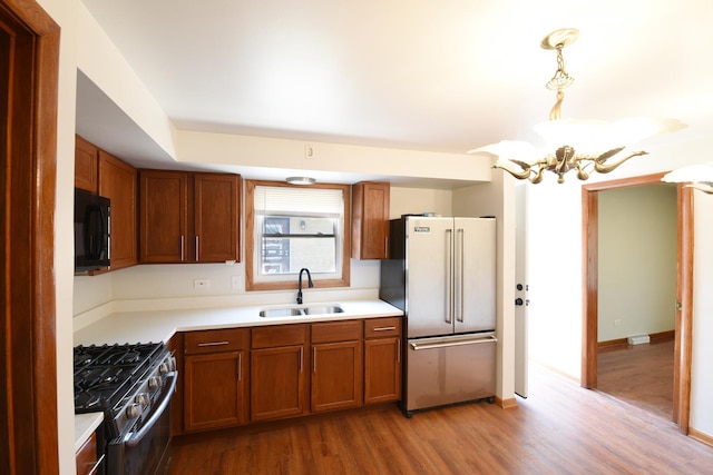 10945 S Lowe Ave, Chicago, IL 60628 - kitchen featuring stainless steel appliances, a sink, brown cabinetry, light wood-style floors, and a chandelier