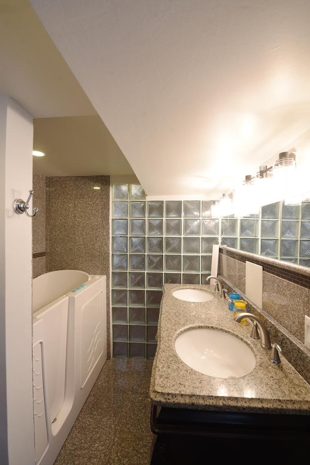 10945 S Lowe Ave, Chicago, IL 60628 - bathroom with granite floors, a bath, double vanity, and tile walls