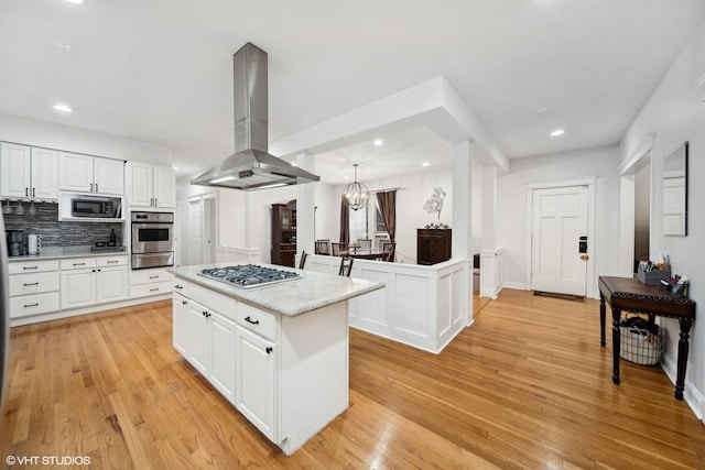 1055 E Hyde Park Blvd Unit 3, Chicago, IL 60615 - kitchen featuring island range hood, appliances with stainless steel finishes, a kitchen island, light wood-style flooring, and white cabinetry
