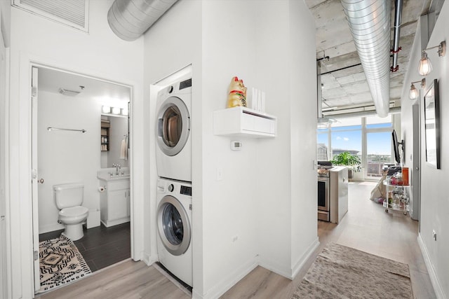 50 E 16th St Unit 1206, Chicago, IL 60616 - washroom featuring estacked washer and dryer, light wood finished floors, and baseboards