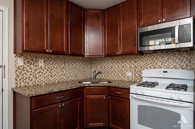 4855 W Roscoe St Unit 1, Chicago, IL 60641 - kitchen featuring white gas stove, stainless steel microwave, tasteful backsplash, and dark stone counters