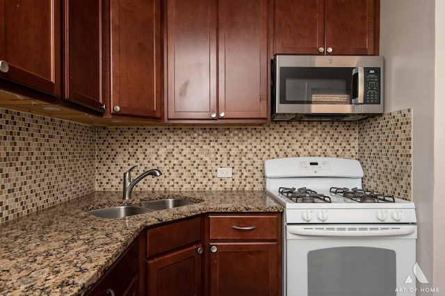 4855 W Roscoe St Unit 1, Chicago, IL 60641 - kitchen with white gas range, stainless steel microwave, decorative backsplash, and dark stone counters