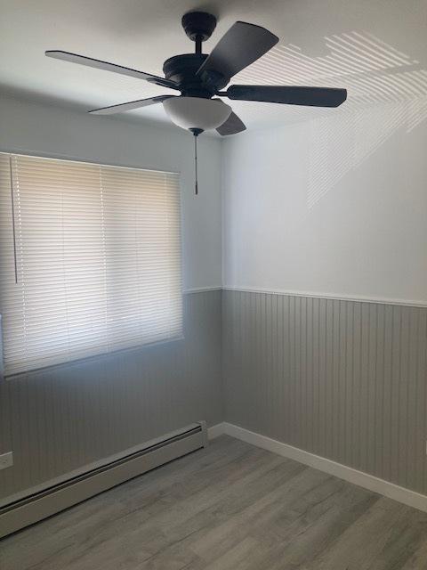 129 Elk Trl W Unit 329, Carol Stream, IL 60188 - empty room with baseboard heating, a wainscoted wall, wood finished floors, and a ceiling fan