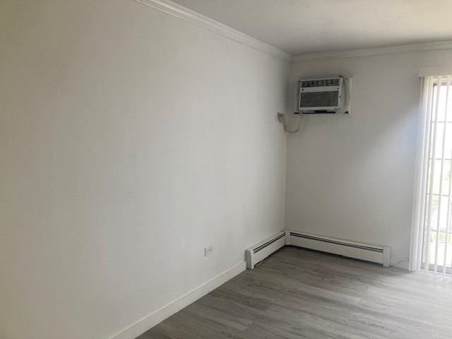 129 Elk Trl W Unit 329, Carol Stream, IL 60188 - empty room with a wall mounted air conditioner, a baseboard radiator, wood finished floors, crown molding, and baseboards