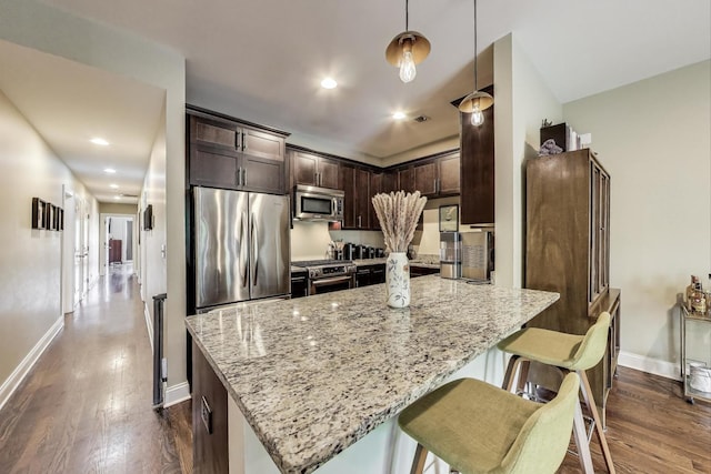 2120 W Rice St Unit 3, Chicago, IL 60622 - kitchen with stainless steel appliances, light stone counters, light wood-style flooring, dark brown cabinetry, and hanging light fixtures