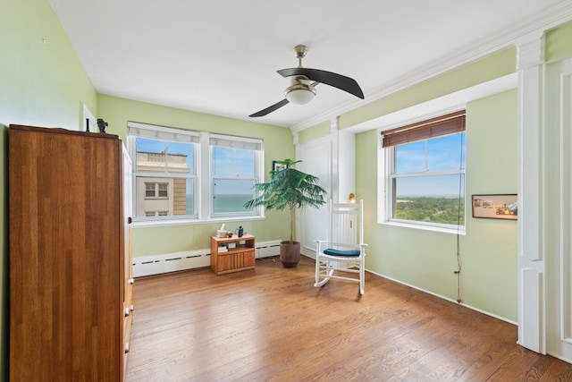 5555 N Sheridan Rd Unit 1906, Chicago, IL 60640 - living area with a baseboard heating unit, wood finished floors, ceiling fan, crown molding, and baseboards