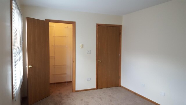 1341 Cunat Ct Unit 1C, Lake In The Hills, IL 60156 - unfurnished bedroom featuring a closet, light colored carpet, and baseboards