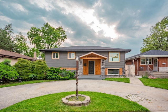 17128 Grant St, Lansing, IL 60438 - raised ranch with curved driveway, a front yard, and stone siding