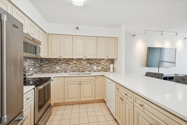 512 N Mcclurg Ct Unit 1009, Chicago, IL 60611 - kitchen featuring appliances with stainless steel finishes, a sink, track lighting, cream cabinetry, and decorative backsplash