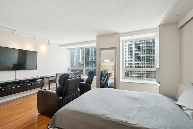 512 N Mcclurg Ct Unit 1009, Chicago, IL 60611 - bedroom featuring rail lighting, wood finished floors, and a textured ceiling
