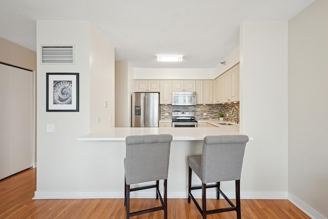 512 N Mcclurg Ct Unit 1009, Chicago, IL 60611 - kitchen featuring stainless steel appliances, cream cabinets, a kitchen breakfast bar, light countertops, and light wood-style flooring