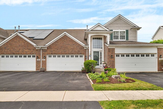 117 Andrew Taras Ct Unit B1, Joliet, IL 60435 - traditional home featuring driveway, brick siding, roof mounted solar panels, roof with shingles, and a garage