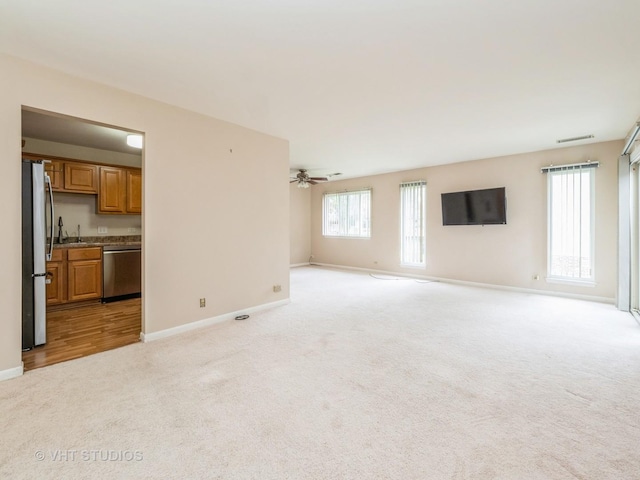 127 Wolcott Ct Unit 2, Schaumburg, IL 60193 - unfurnished living room featuring light colored carpet, a sink, baseboards, and ceiling fan