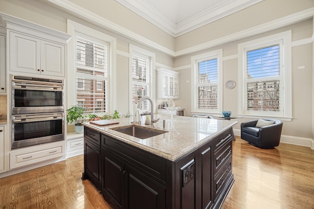 201 Reber St Unit 6, Wheaton, IL 60187 - kitchen with stainless steel double oven, white cabinetry, light wood-type flooring, light stone counters, and a kitchen island with sink