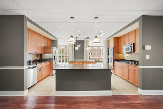 201 Reber St Unit 6, Wheaton, IL 60187 - kitchen featuring stainless steel appliances, a paneled ceiling, a kitchen island, decorative light fixtures, and light wood-style flooring