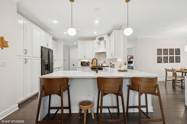 50 W Kennedy Ln Unit 102, Hinsdale, IL 60521 - kitchen with black fridge with ice dispenser, custom range hood, stainless steel microwave, a kitchen breakfast bar, and recessed lighting