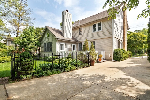 674 Foxdale Ave, Winnetka, IL 60093 - back of house featuring a chimney, concrete driveway, a patio, and a shingled roof