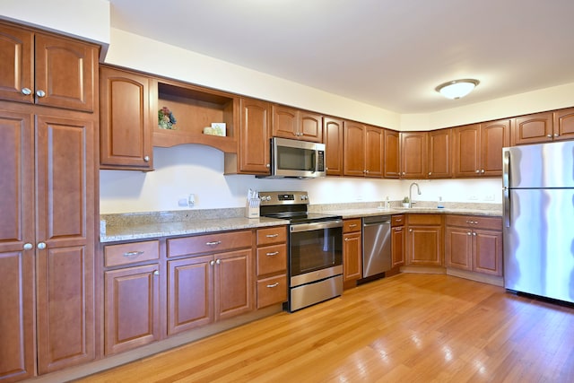 505 N Kenilworth Ave Unit 3, Glen Ellyn, IL 60137 - kitchen featuring appliances with stainless steel finishes, a sink, light wood-style flooring, light stone counters, and open shelves