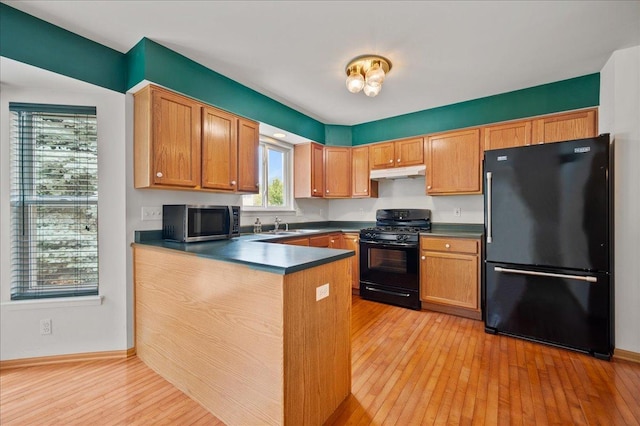 249 Spring Ct, North Aurora, IL 60542 - kitchen with black appliances, under cabinet range hood, dark countertops, a peninsula, and light wood-style flooring