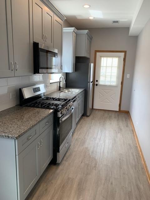 3116 S Canal St, Chicago, IL 60616 - kitchen featuring stainless steel appliances, a sink, light wood-style flooring, gray cabinetry, and baseboards