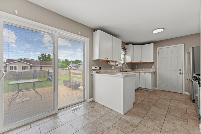 5724 Pierce Ln, South Beloit, IL 61080 - kitchen with white cabinets, light countertops, baseboards, a sink, and light tile patterned flooring