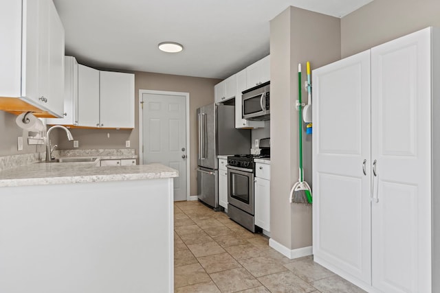 5724 Pierce Ln, South Beloit, IL 61080 - kitchen featuring appliances with stainless steel finishes, a sink, white cabinets, a peninsula, and baseboards