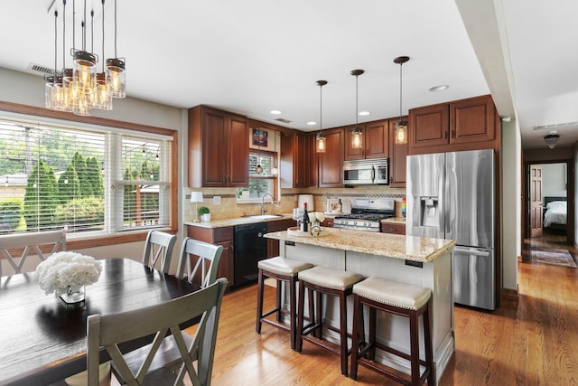 11111 Doogan Ave, Willow Springs, IL 60480 - kitchen featuring appliances with stainless steel finishes, a sink, tasteful backsplash, light wood finished floors, and a center island