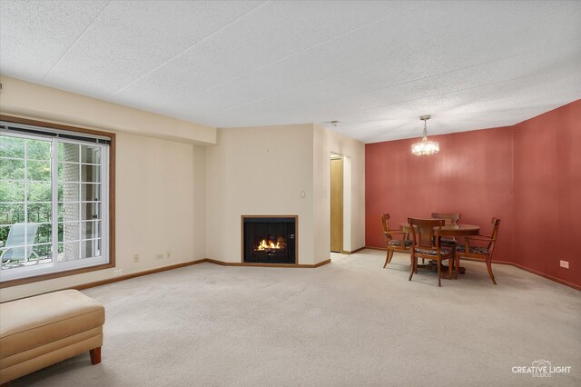unfurnished dining area featuring light carpet, a chandelier, baseboards, and a textured ceiling