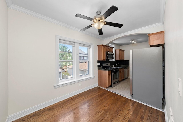 4860 W Warner Ave Unit 1, Chicago, IL 60641 - kitchen with stainless steel appliances, dark countertops, crown molding, brown cabinetry, and a sink