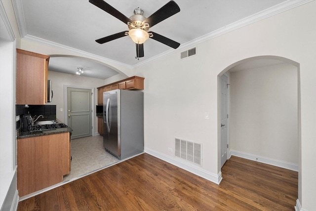 4860 W Warner Ave Unit 1, Chicago, IL 60641 - kitchen with stainless steel appliances, arched walkways, dark countertops, brown cabinets, and crown molding