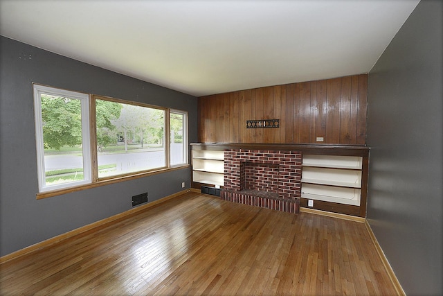 610 E Main St, Ottawa, IL 61350 - unfurnished living room featuring wood-type flooring, baseboards, a fireplace, and wooden walls