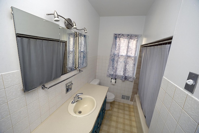 610 E Main St, Ottawa, IL 61350 - bathroom with tile walls, toilet, vanity, wainscoting, and tile patterned floors