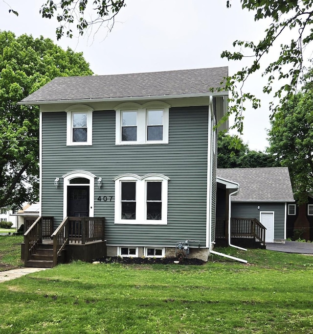 view of front of home with a front yard and a shingled roof