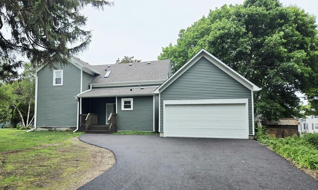 view of front of property with driveway, an attached garage, and a shingled roof