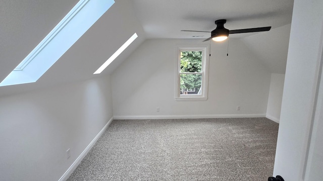 bonus room featuring a skylight, carpet flooring, lofted ceiling, baseboards, and ceiling fan