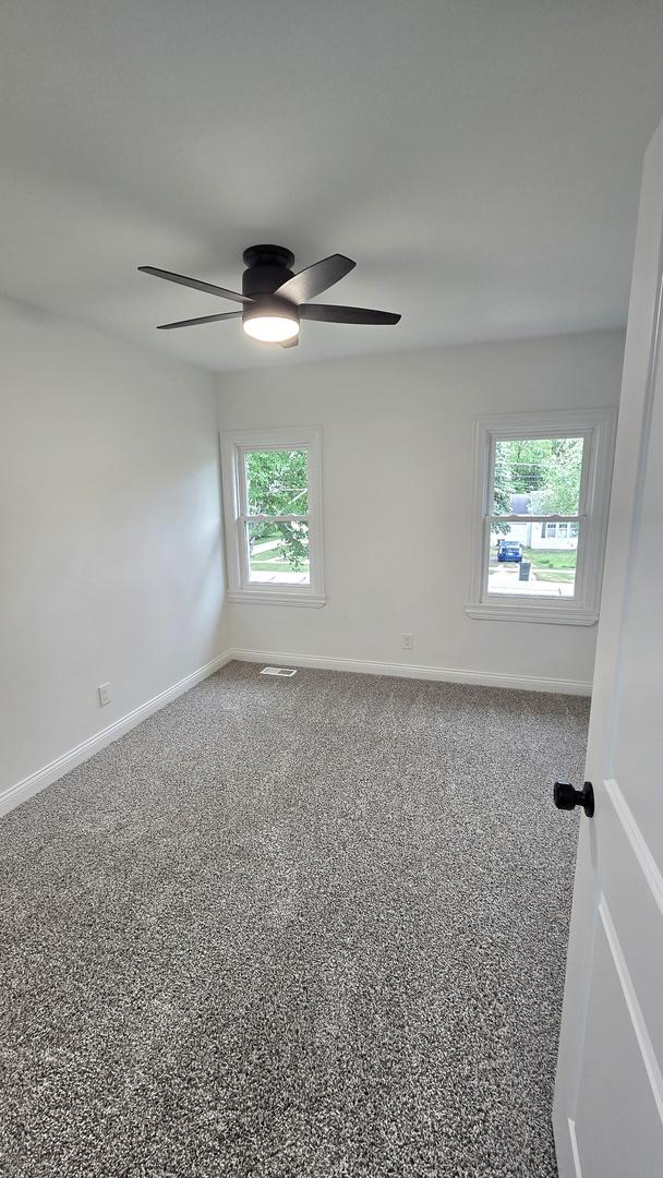 spare room with a ceiling fan and baseboards