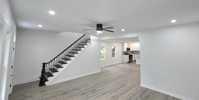 unfurnished living room with stairs, recessed lighting, light wood-style flooring, ceiling fan, and baseboards