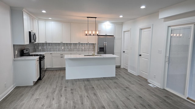kitchen with gas range oven, stainless steel fridge, light wood-style floors, decorative backsplash, and recessed lighting