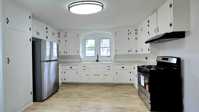 kitchen with freestanding refrigerator, under cabinet range hood, black range with gas stovetop, light wood-type flooring, and a sink